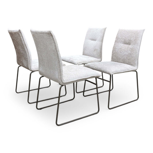 Full view of Set of four Connubia Maya dining chairs featuring sand-colored fabric upholstery and contemporary lava-finish metal ski-style legs.