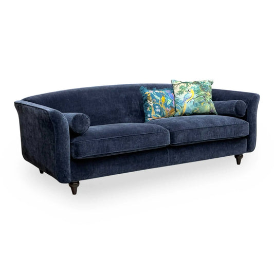 Full view DFS ‘Dame’ 4-seater sofa in a deep navy blue plain fabric, featuring matching bolster cushions.