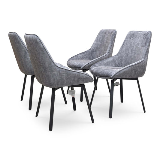 Full view of two 'Veja' dining chairs upholstered in luxurious grey velvet, featuring a modern bucket-style seat and sleek black metal legs.