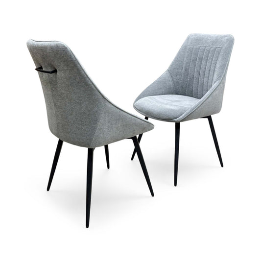 Full view of a pair of 'Crete' modern swivel dining chairs in silver fabric, featuring a contoured curved backrest and a sleek black metal four-star spider base.