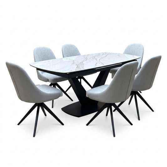 Jose white marble effect ceramic extending dining table with six stone grey faux leather swivel chairs, angled view