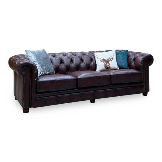At The Helm Shackleton burgundy leather 4 seater Chesterfield sofa, angled view with stag and velvet cushions