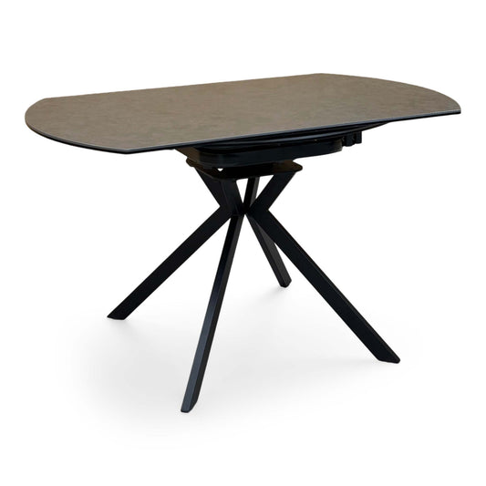 Quattro dark grey ceramic swivel dining table in its closed oval position, angled view on black legs