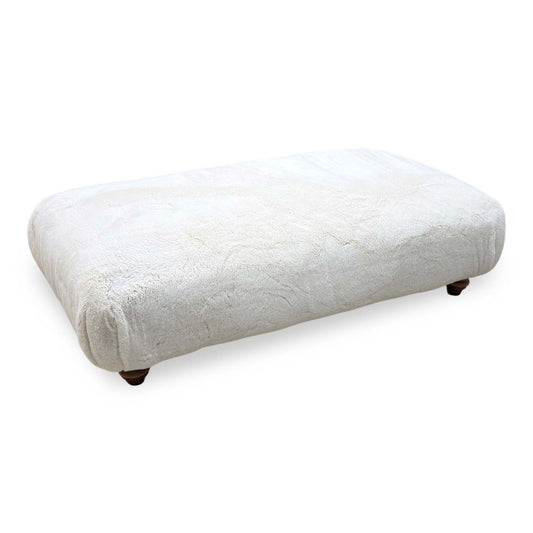 Blenheim Darwin ivory faux fur large footstool on dark wooden bun feet, angled from the right