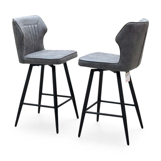Jayden dark grey faux leather pair of swivel bar stools with black metal legs and footrests, angled view from the left