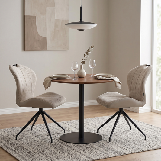 Dining room view of the Raul set of 2 swivel dining chairs in pebble taupe fabric, showcasing their modern bucket seat design, vertical channel tufting, and black metal tapered legs.