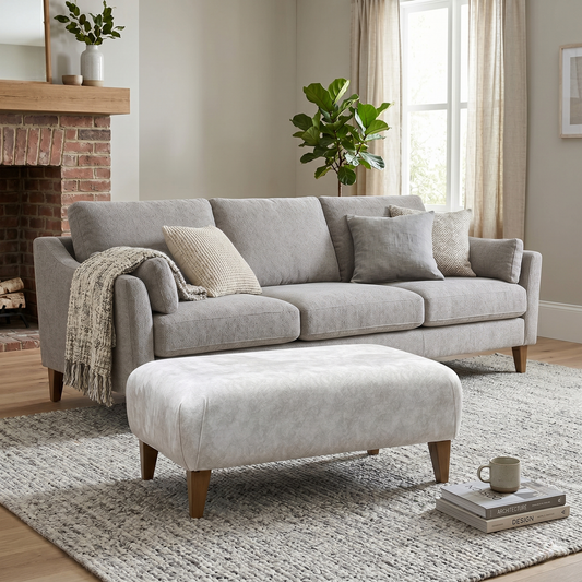 Living room view of Aura Kenzo designer cream fabric footstool. Showcase image highlighting the uniform square proportions, premium piping trim details, and sturdy structural build engineered for use as a footrest or extra lounge seating.