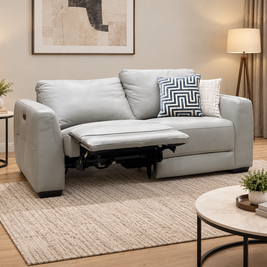 Dinky light grey leather power recliner sofa in a living room with one seat reclined, beside a round coffee table