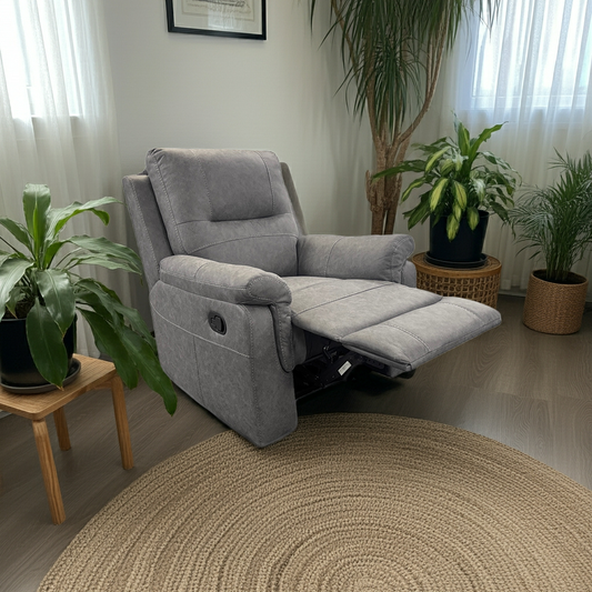 Gray recliner chair in a living room with plants and a round rug.