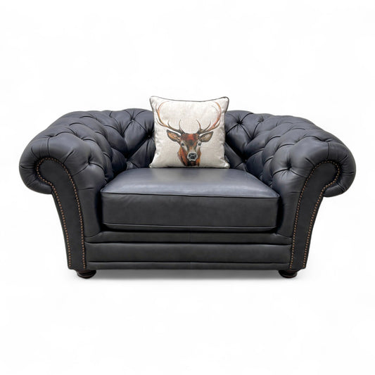 Close-up of the navy blue leather upholstery on the 'Savannah' snuggler chair, emphasizing the smooth texture and solid color.