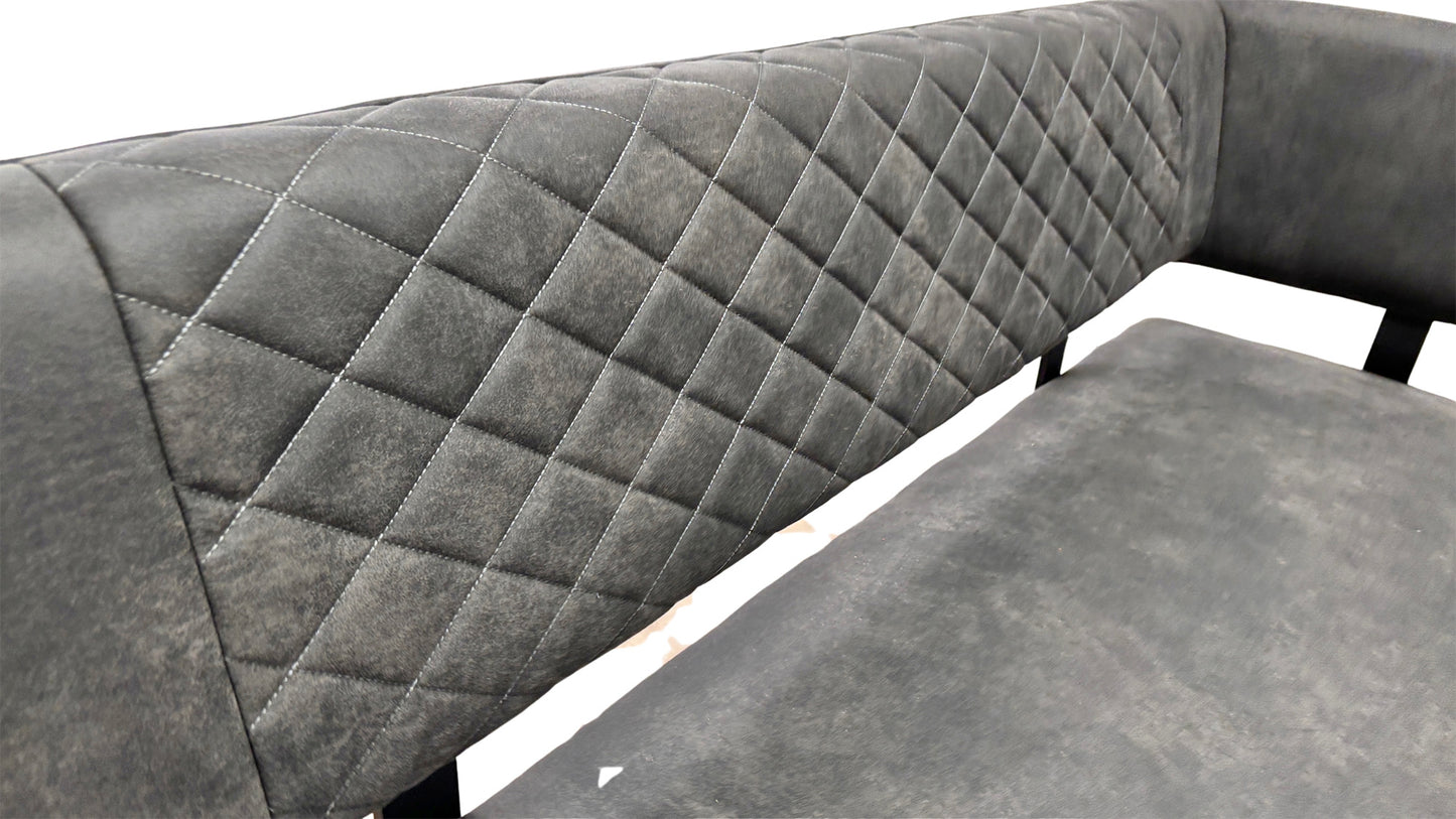 Close-up side view of the corner bench, showcasing the high backrest, the quilted stitching pattern on the grey fabric, and the metal legs.