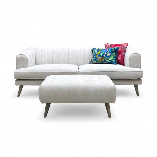 An angled view of the sofa and footstool, showing the clean lines and overall profile of the set.
