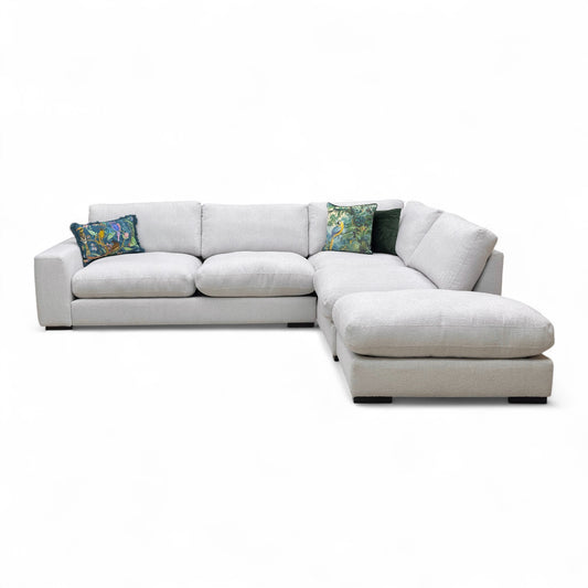 Full front-angled view of the large ‘Corey’ Corner Sofa in ivory chord fabric, showcasing the open-end chaise lounge on the right.