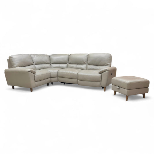 The complete Silverstone compact corner sofa set in lead grey leather, featuring a left-hand facing power recliner and a matching storage footstool in a modern living room.
