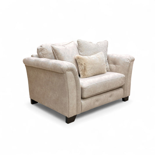 Beige fabric snuggler armchair with rolled arms and accent pillows.