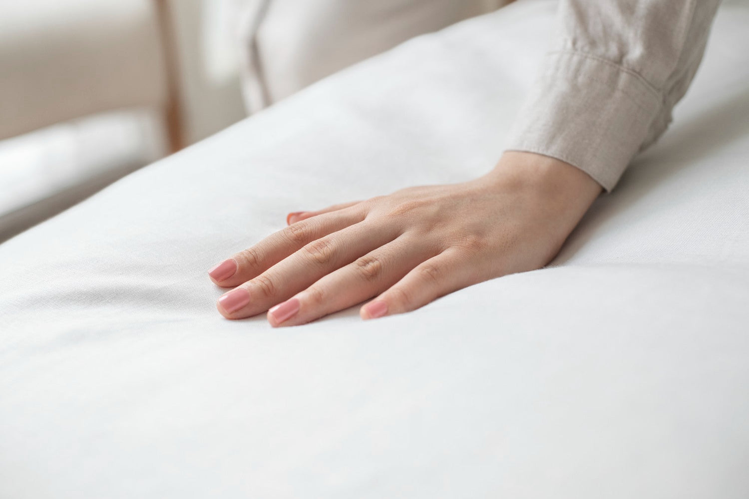 A hand gently resting on a mattress surface, showcasing the softness and comfort of mattresses.