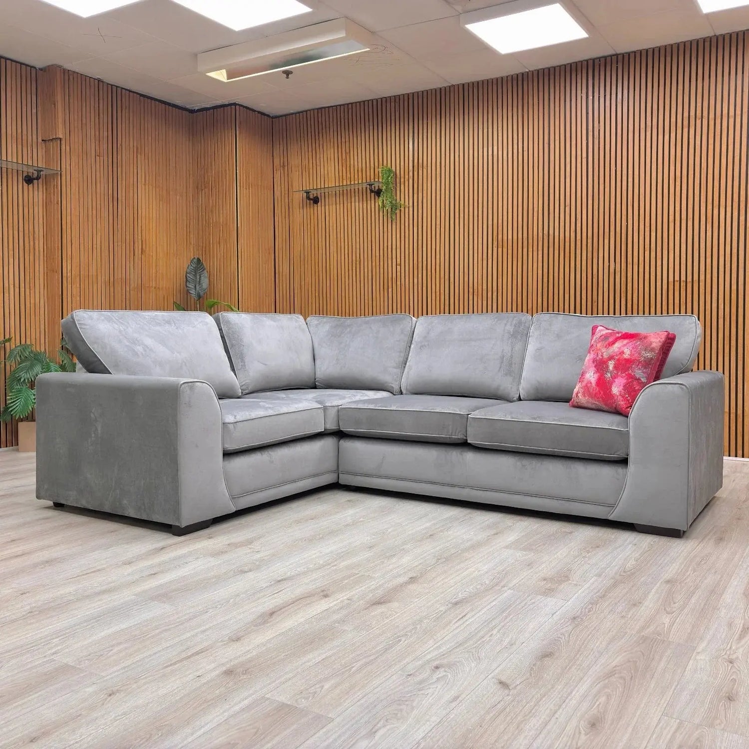 Corner sofa in a modern living room setting with wood paneling and a decorative pillow.