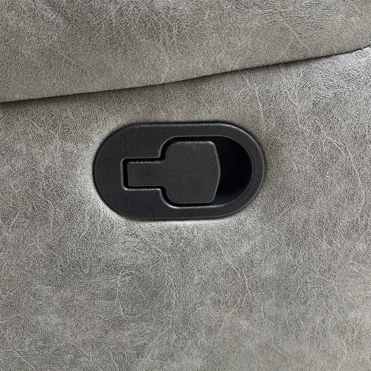 Detail shot of the black manual handle or latch used to operate the footrest and recliner mechanism on the side of the sofa.