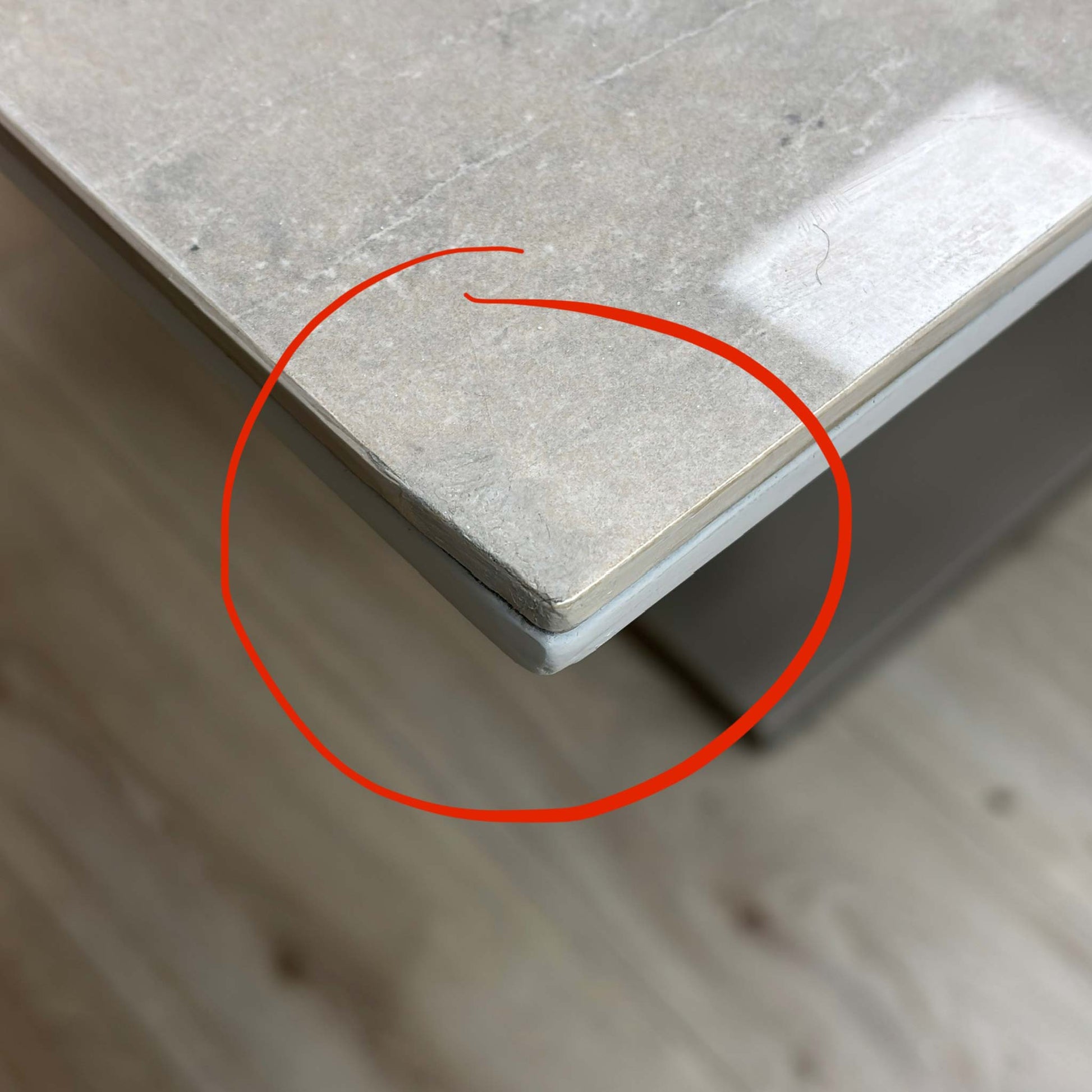 Close-up of the specific corner damage, showing the chipped and slightly crushed ceramic edge as described in the listing.