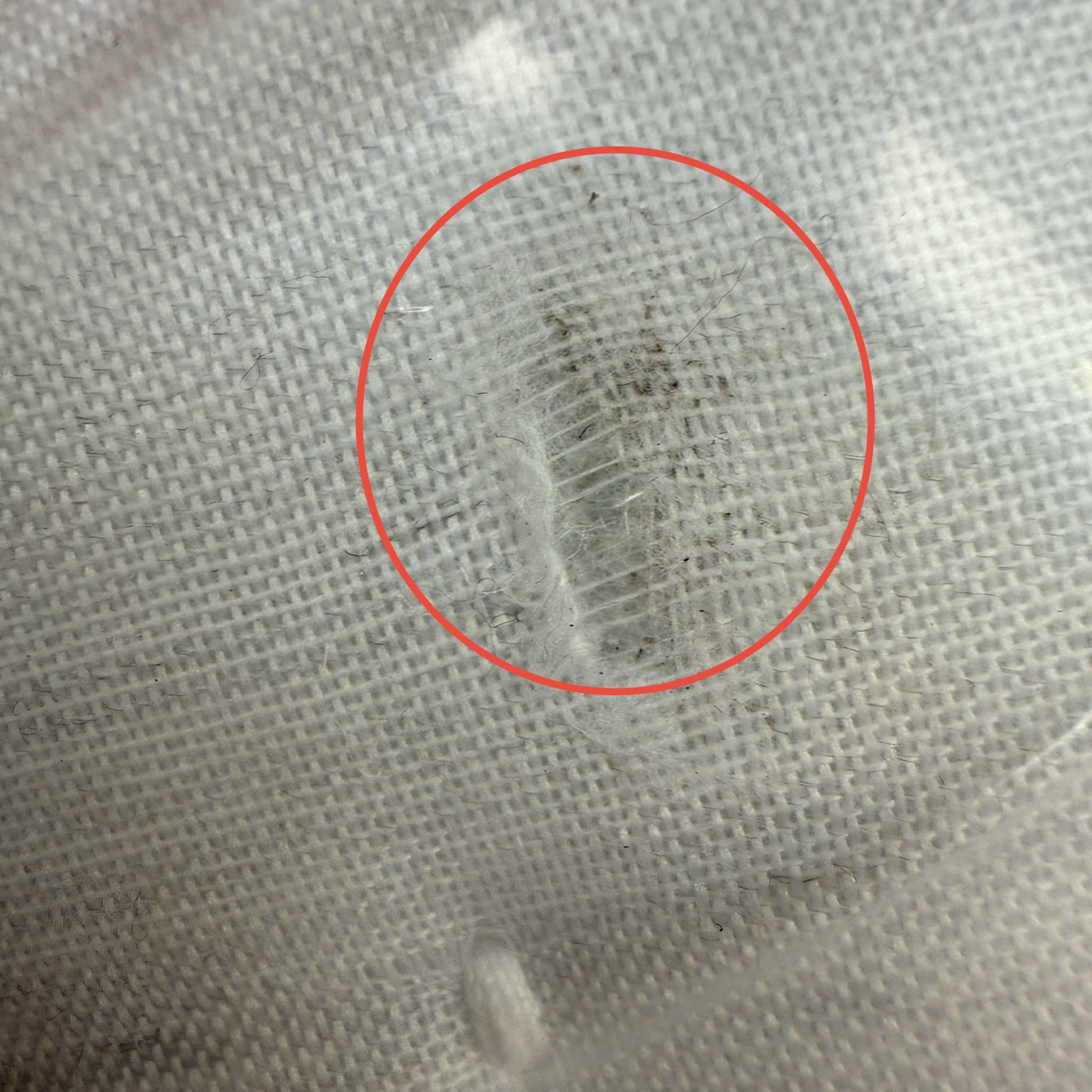 A detailed close-up of the mattress side border showing a visible scuff mark and slight surface soiling on the dark grey fabric near the chrome air vent.