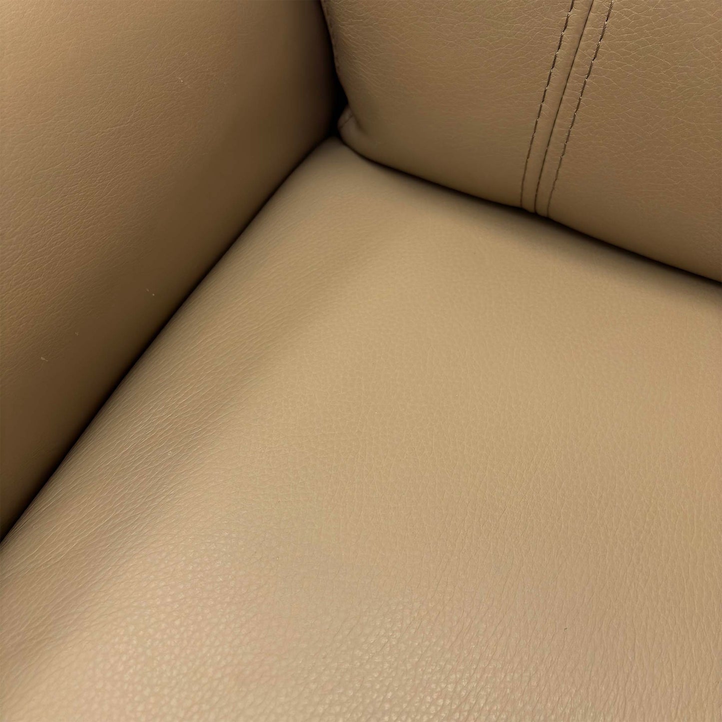 Close-up of the smooth Taupe Leather upholstery, highlighting the padded armrest and high back design.