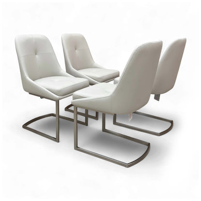 Angled view of the 'Avorio' Set of 4 Neutral Faux Leather Dining Chairs, showcasing their sleek design and cantilever chrome legs.