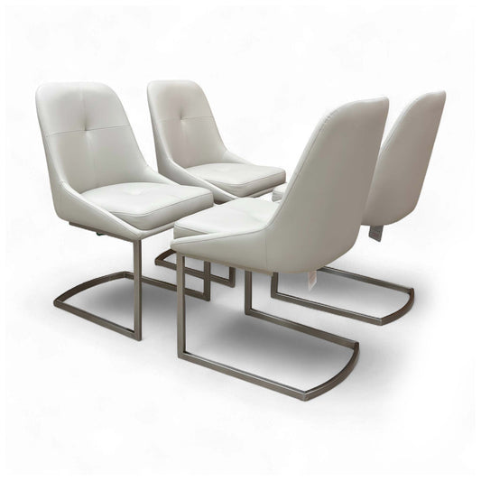 Angled view of the 'Avorio' Set of 4 Neutral Faux Leather Dining Chairs, showcasing their sleek design and cantilever chrome legs.
