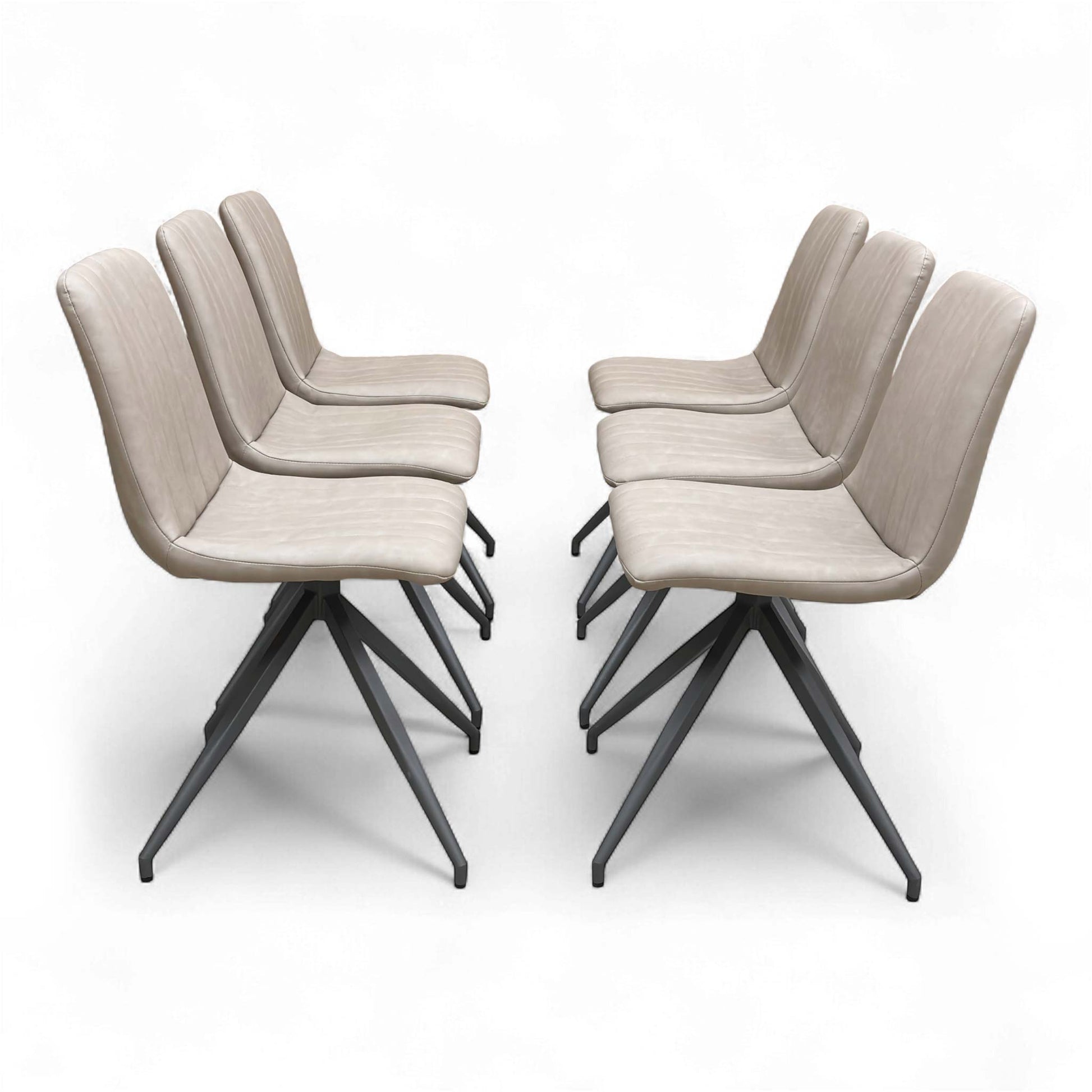 A contemporary dining setting showing four of the six ‘Isaac’ Taupe Faux Leather Dining Chairs arranged around a dining table.