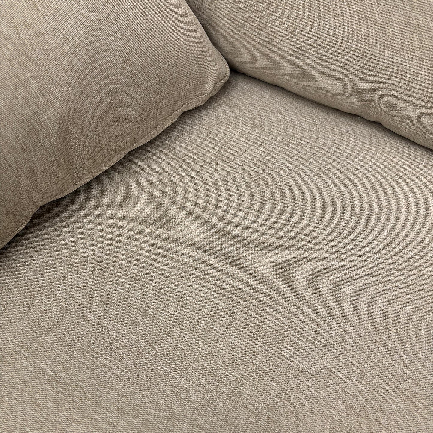 Detailed close-up of the Novak Biscuit soft tight weave fabric, illustrating the upholstery texture and the design of the sloped armrest.