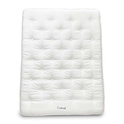 Full view of the King-size Harrison Spinks 'Conrad' 15750 Pocket Spring Mattress, featuring a luxurious white tufted top and firm vertical side stitching, displayed on a wooden base.