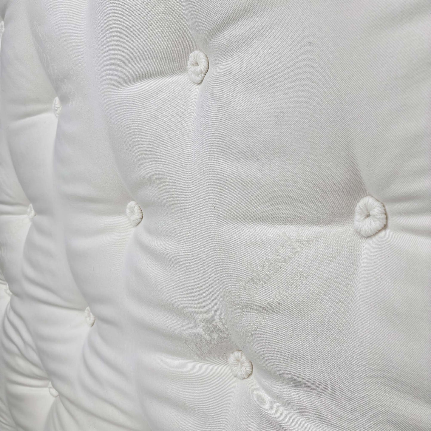 Detailed close-up of the luxurious, quilted white top fabric with deep tufting, illustrating the edge support and craftsmanship.