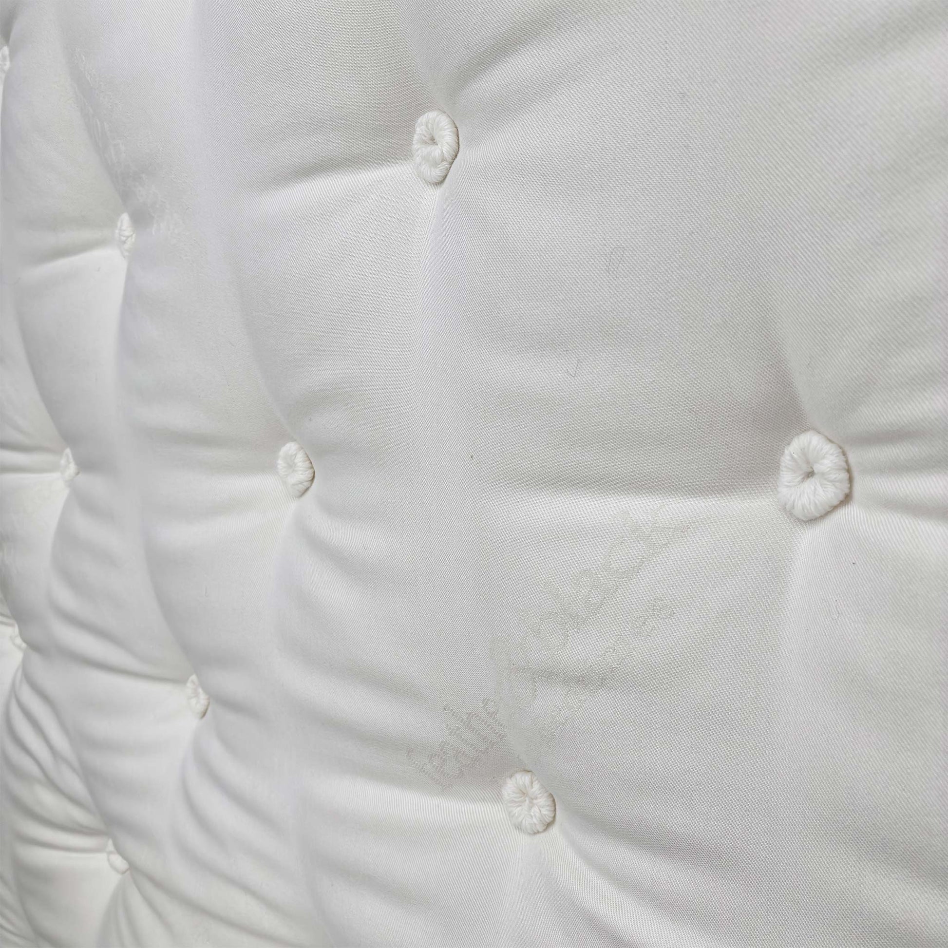 Detailed close-up of the luxurious, quilted white top fabric with deep tufting, illustrating the edge support and craftsmanship.