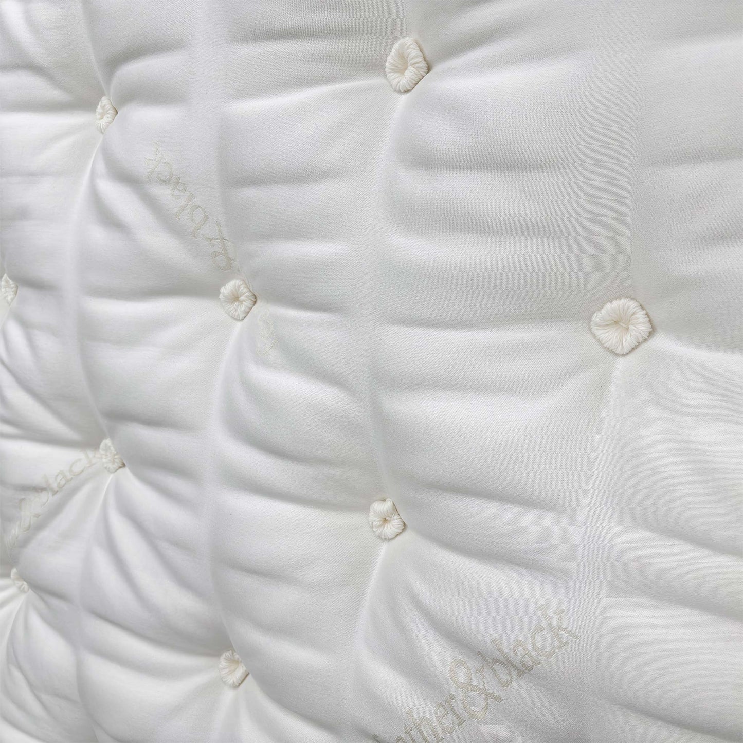 Detailed close-up of the sumptuous pillow-top sleeping surface, showcasing the natural fillings like silk, cashmere, mohair, and British wool.