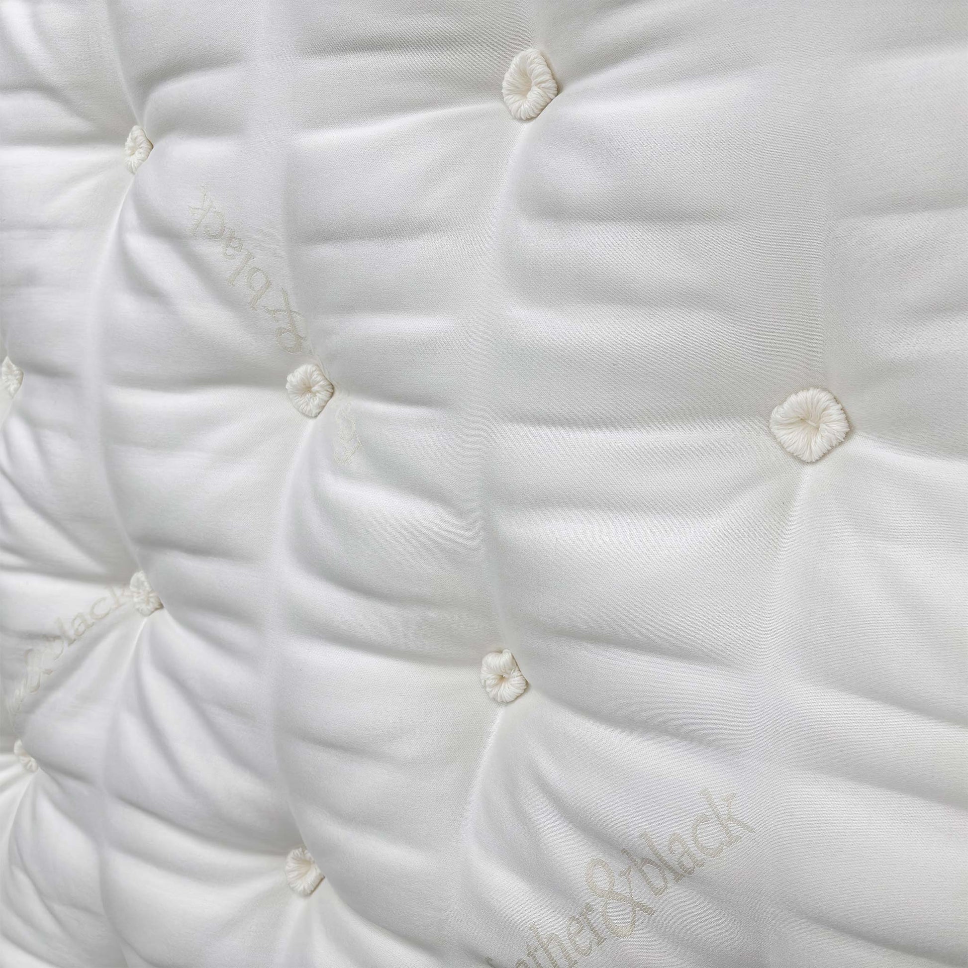 Detailed close-up of the sumptuous pillow-top sleeping surface, showcasing the natural fillings like silk, cashmere, mohair, and British wool.