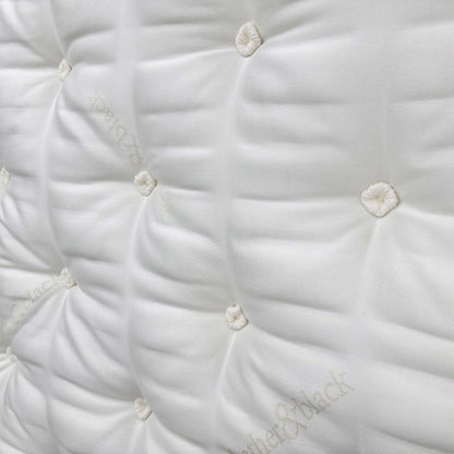 Detailed close-up of the sumptuous pillow-top sleeping surface, showcasing the natural fillings like silk, cashmere, mohair, and British wool.