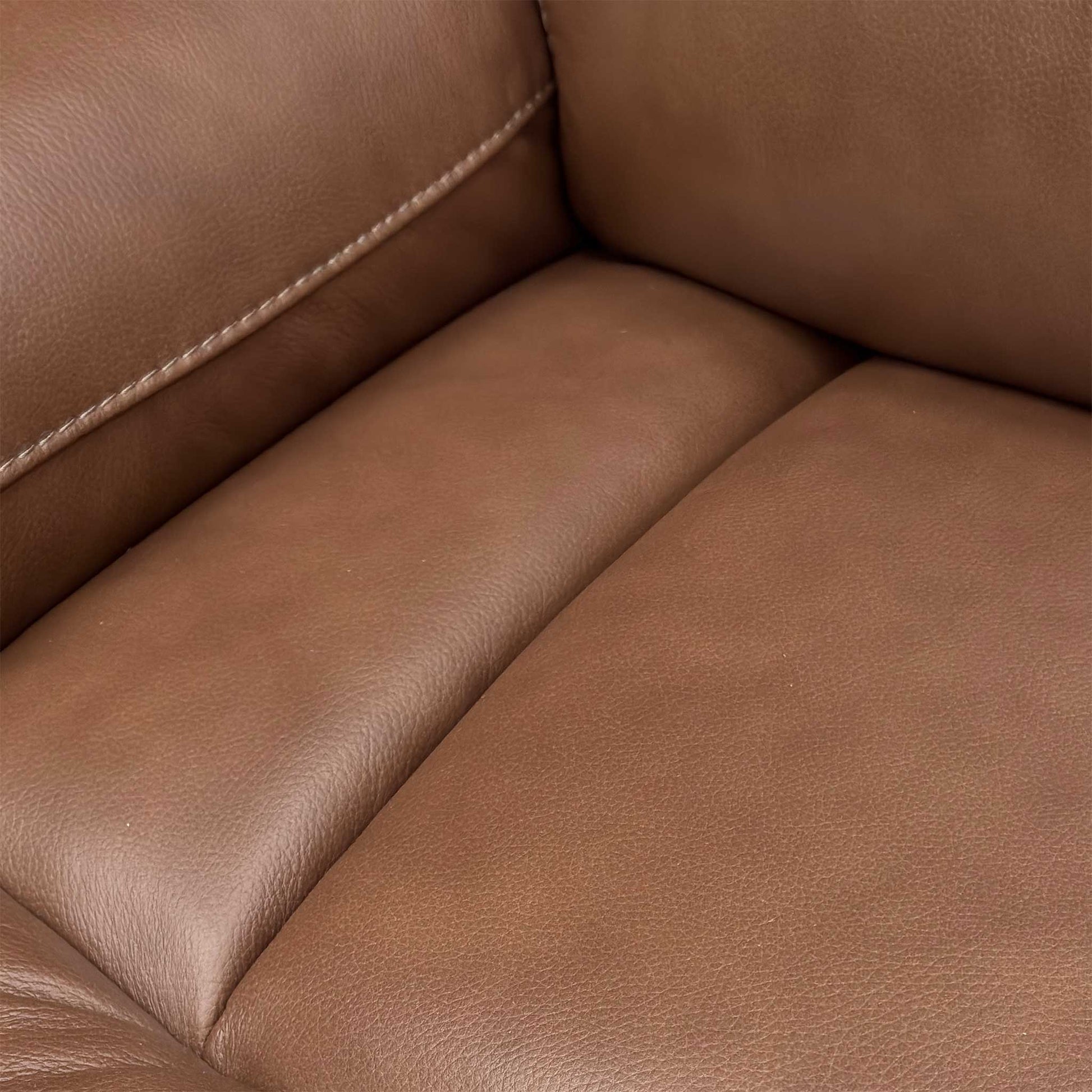 Detail shot of the Roast Brown leather texture on the armrest and side panel of the Cinemax Sofa.