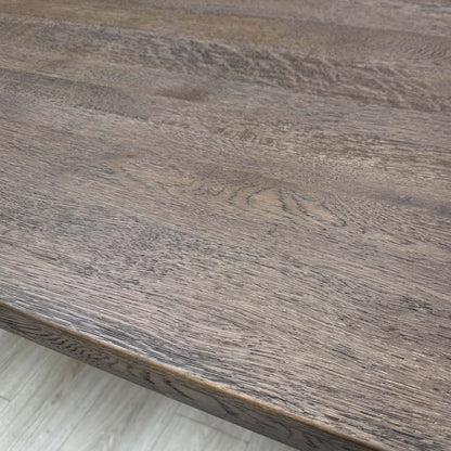Close-up showing the connection point between the dark oak tabletop and the metal legs.