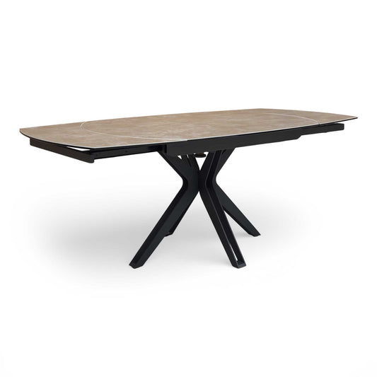 View of the Jose swivel extending dining table featuring a dark steel ceramic boat-shaped top and black star legs.