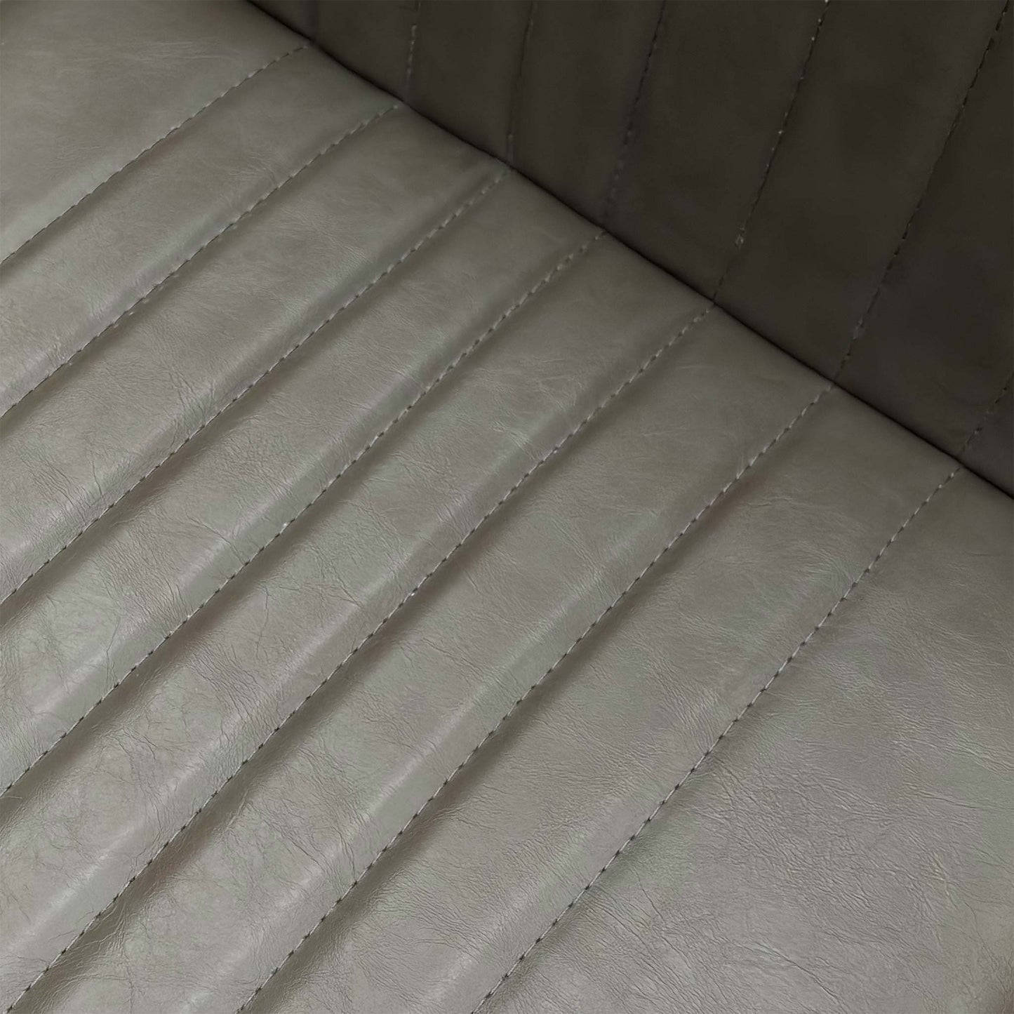Close-up of the grey faux leather upholstery and stitching details on the Arthur dining seat.