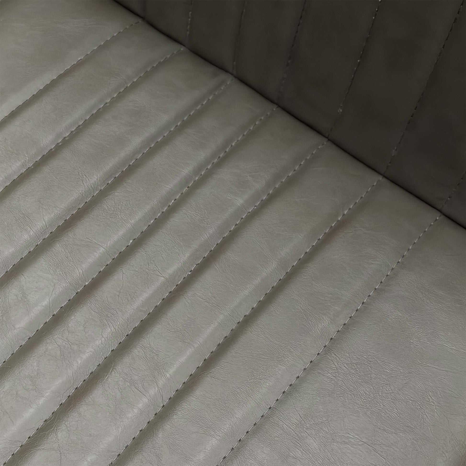 Close-up of the grey faux leather upholstery and stitching details on the Arthur dining seat.