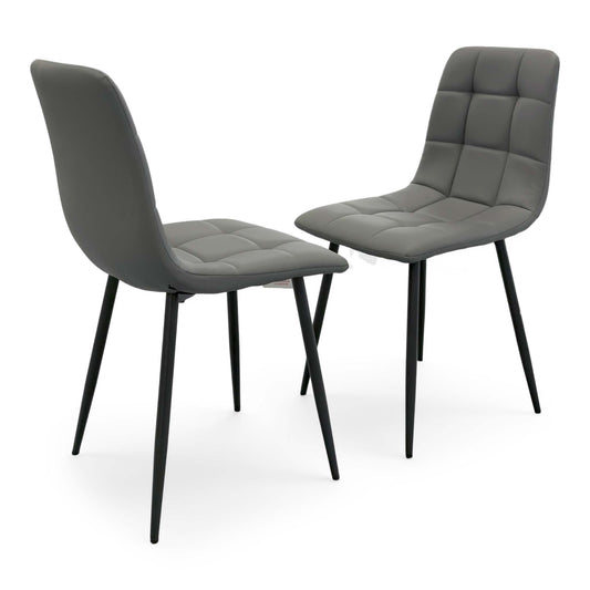 Full view of a set of two Maya Fixed Dining Chairs in Grey Faux Leather, featuring a contemporary industrial design with horizontal bucket-style stitching and black metal legs.