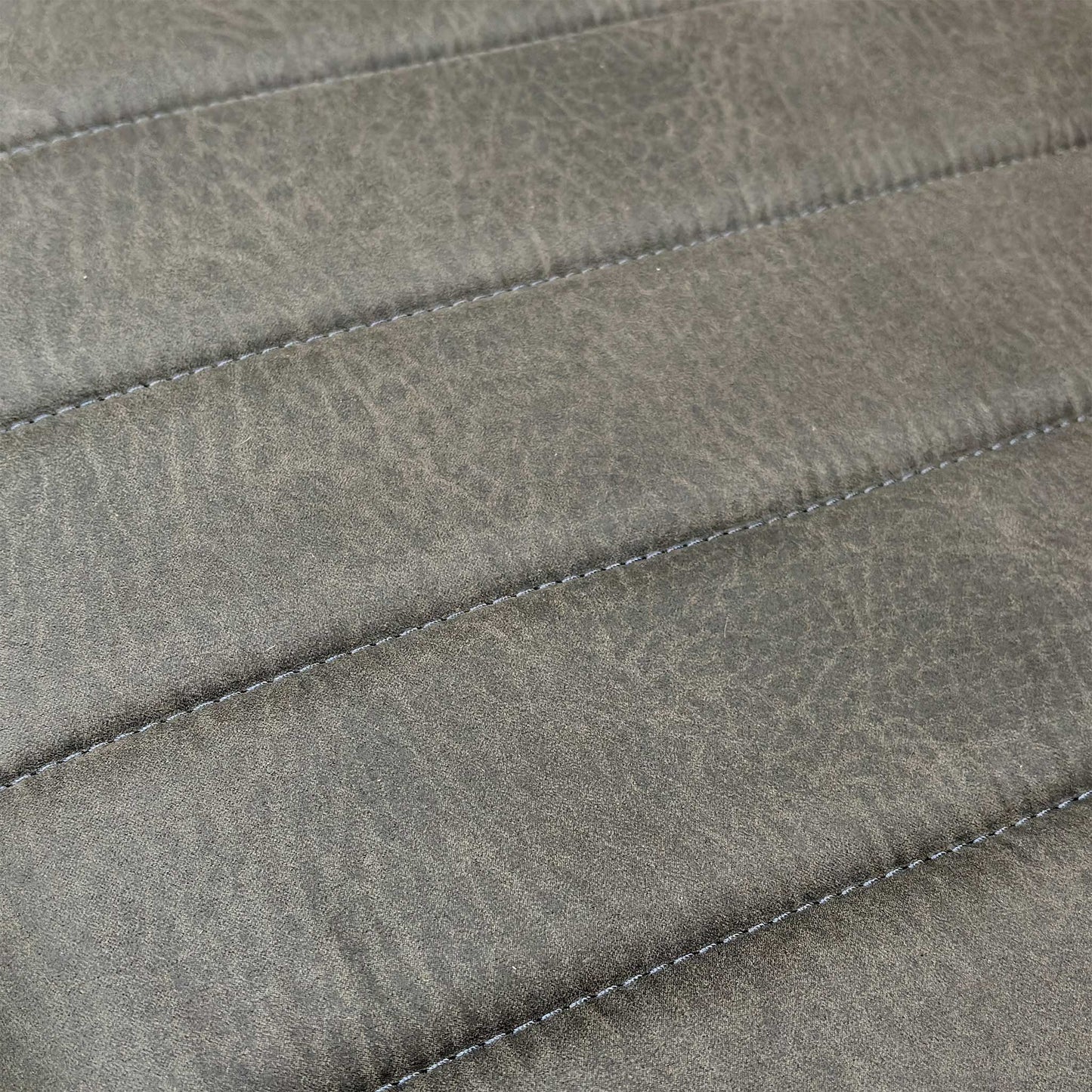 Close-up of the dark grey faux leather upholstery and fluted stitching detail on the bench seat.