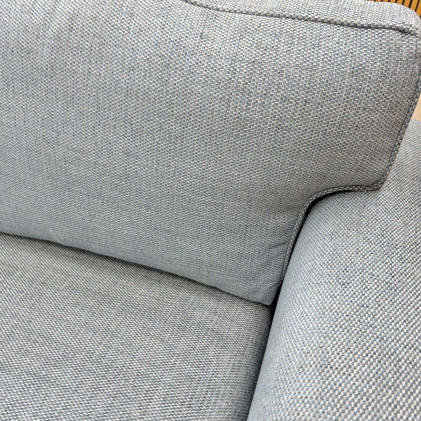 Close-up of the woven fabric texture and piping detail on the sofa's cushions.