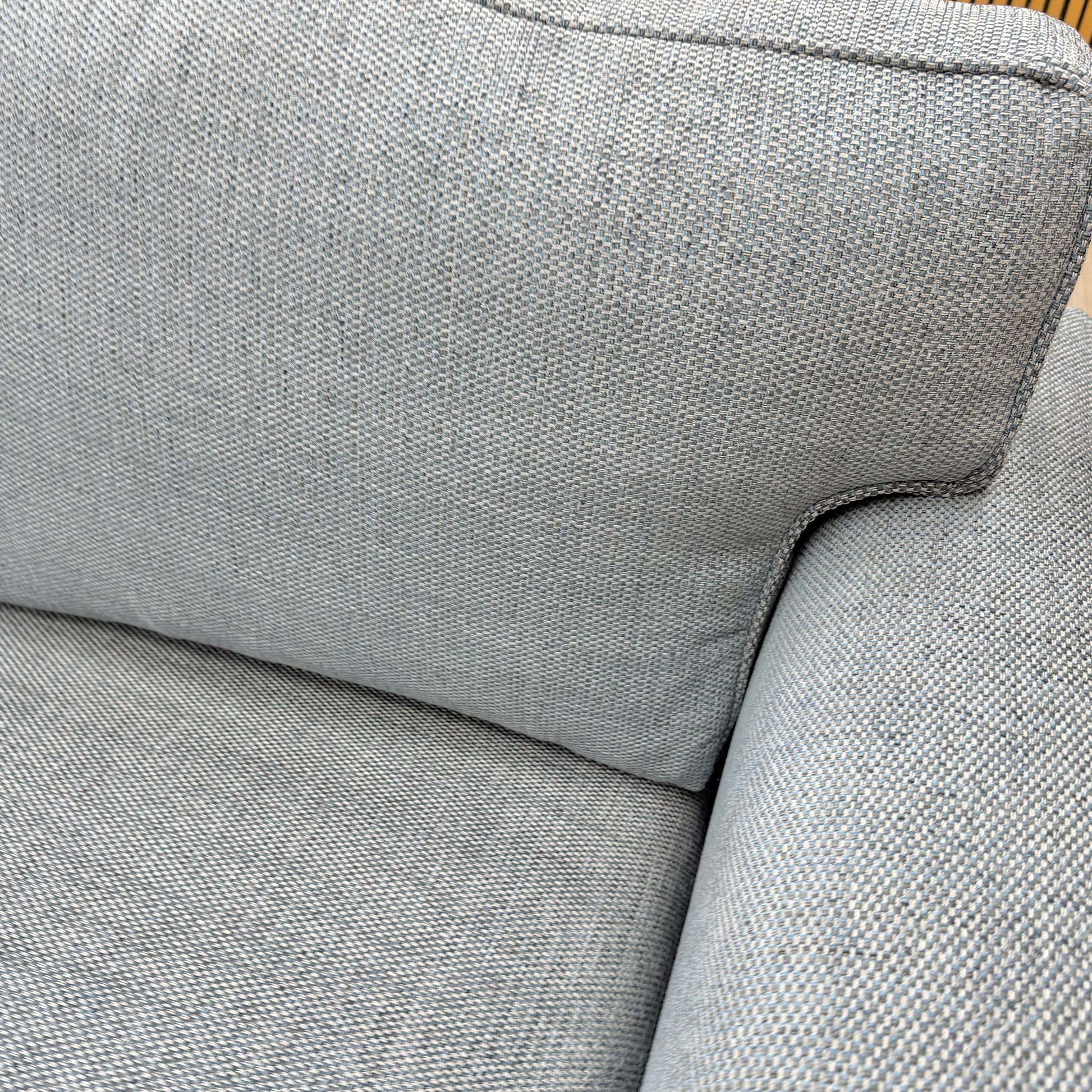 Close-up of the woven fabric texture and piping detail on the sofa's cushions.