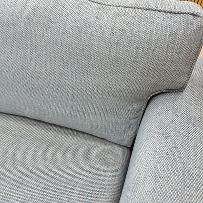 Close-up of the woven fabric texture and piping detail on the sofa's cushions.