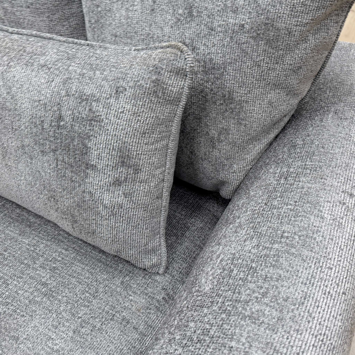 Close-up of the scatter back cushions, illustrating the varied sizes and supportive design of the grey fabric upholstery.