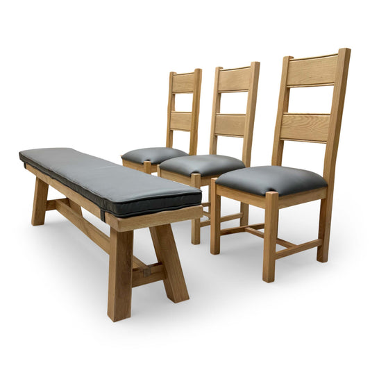 Full view of the 'Delaney' dining set featuring two grey faux leather upholstered chairs with wooden slat backs and a large matching dining bench.
