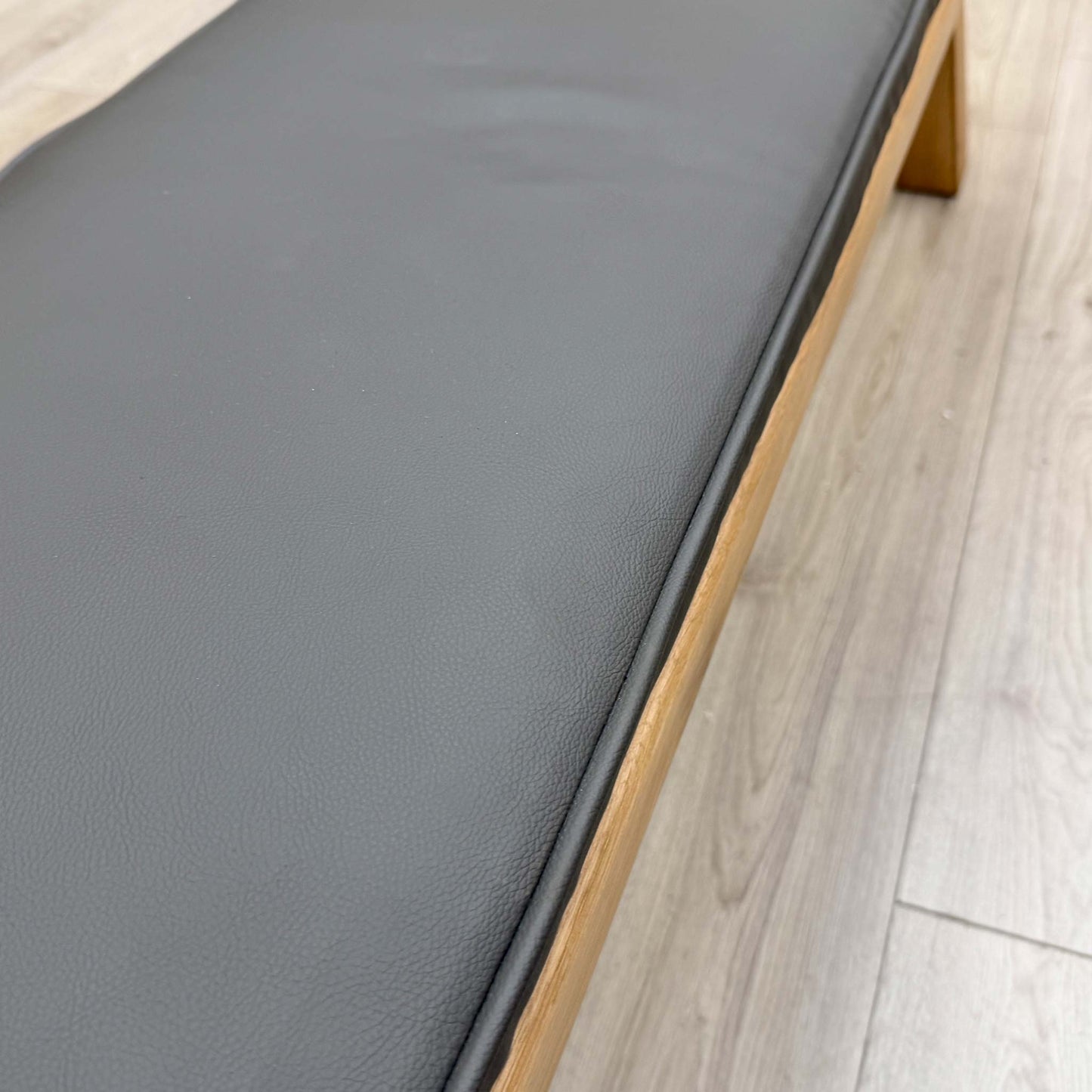 Close-up of the grey faux leather upholstery on the dining bench, showing the smooth, easy-to-clean surface and quality padding.