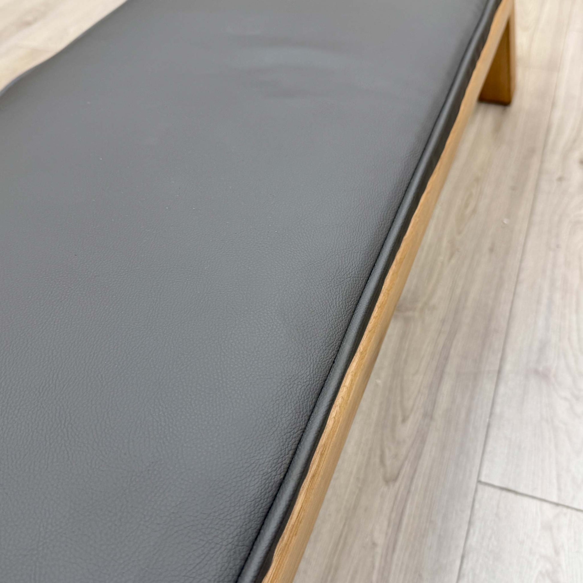 Close-up of the grey faux leather upholstery on the dining bench, showing the smooth, easy-to-clean surface and quality padding.
