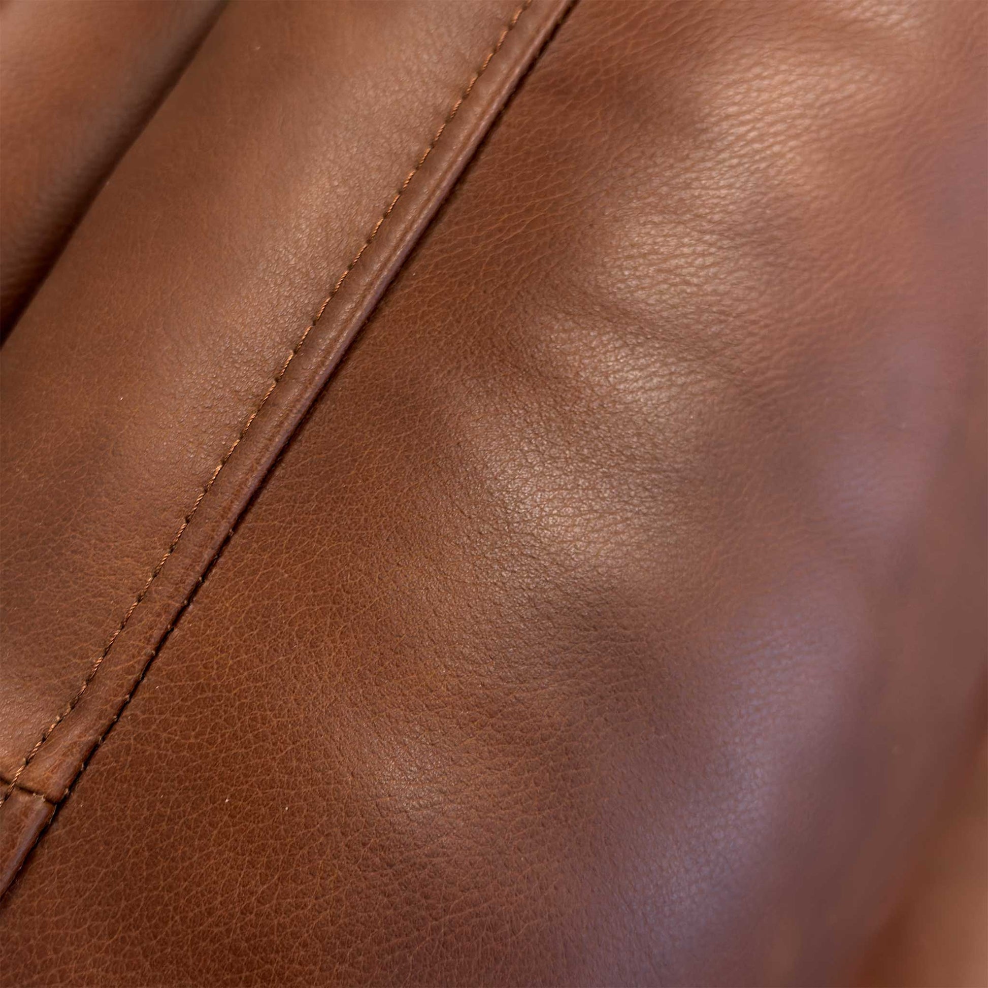 Close-up of the Butterscotch leather upholstery, detailing the high-grade natural grain, soft texture, and precision seam stitching.